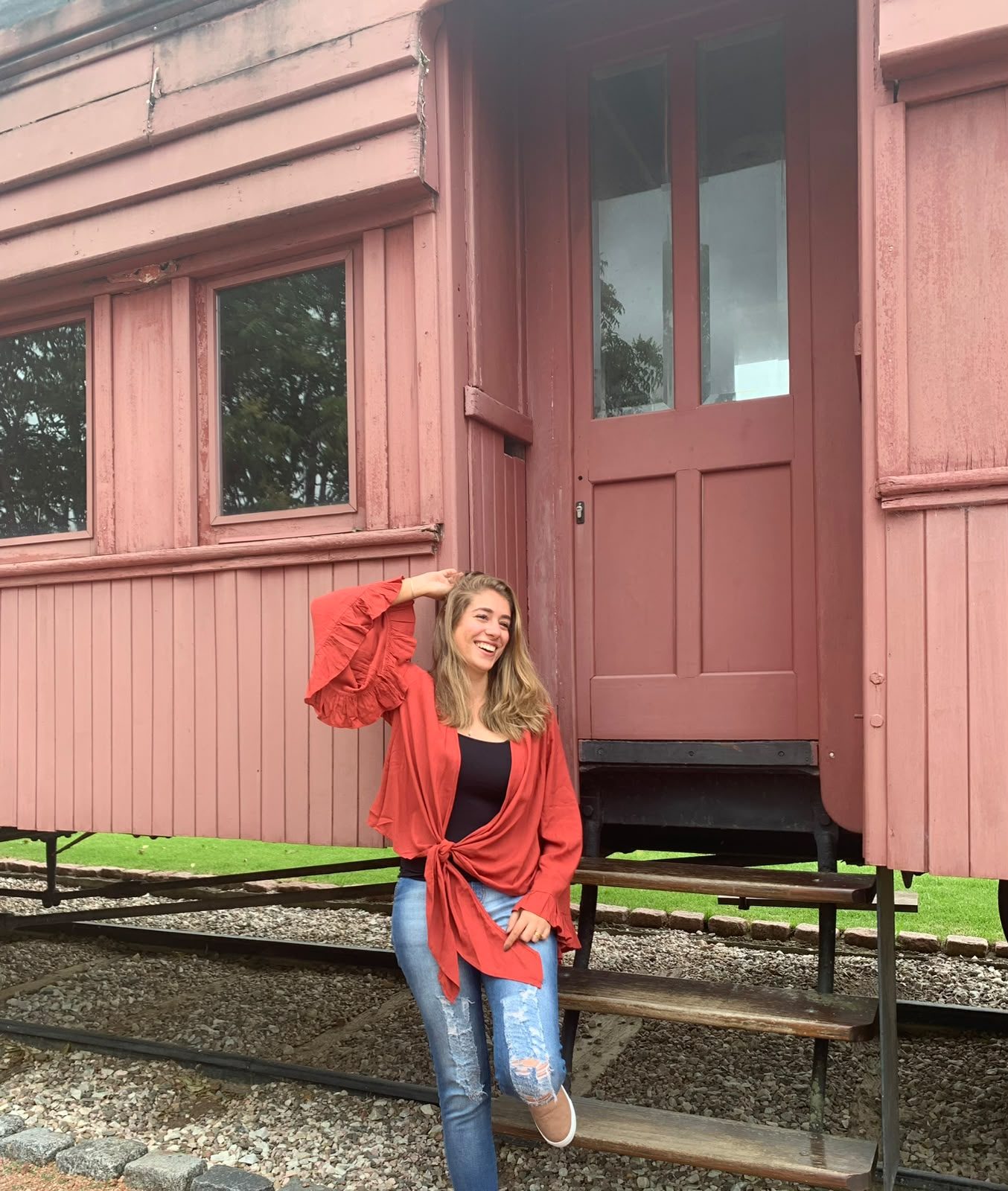 Carol encostada em um vagão de trem histórico