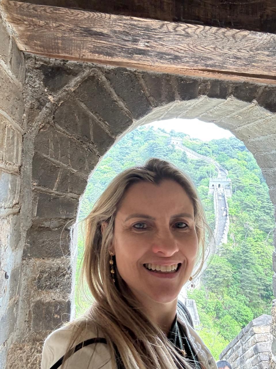 Andrea sob um arco de pedra na Muralha da China